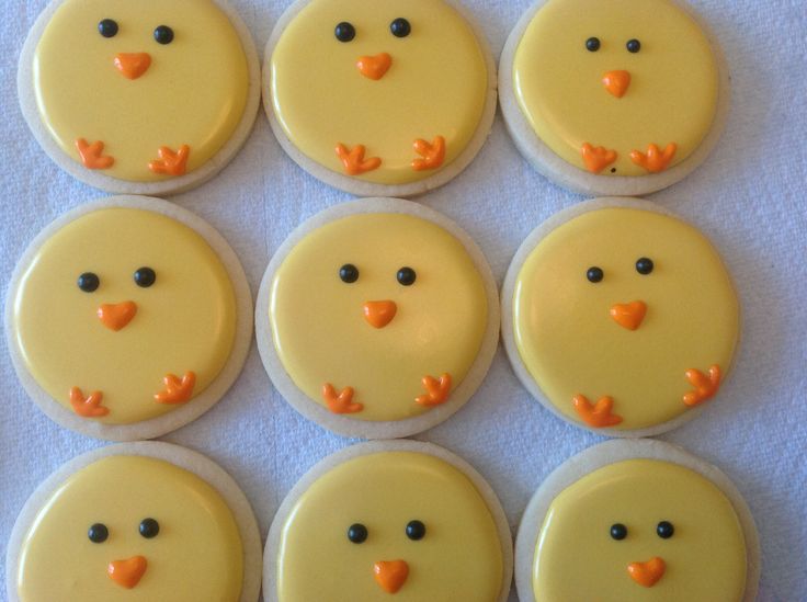 six yellow frosted cupcakes with black eyes and orange nose noses are arranged in rows on a white tablecloth