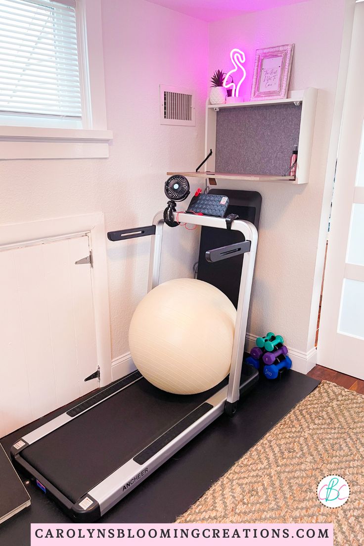 a room with a treadmill, exercise ball and computer on the desk in it