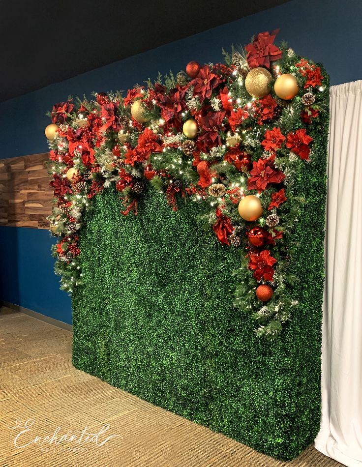 a green wall decorated with christmas decorations and greenery for a holiday party or event