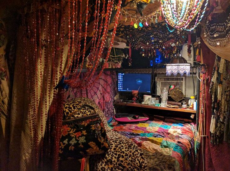 a bed with lots of colorful beads hanging from it's sides and a desk in the middle