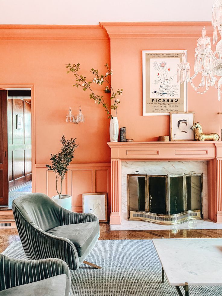 an orange living room with two chairs and a chandelier hanging from the ceiling