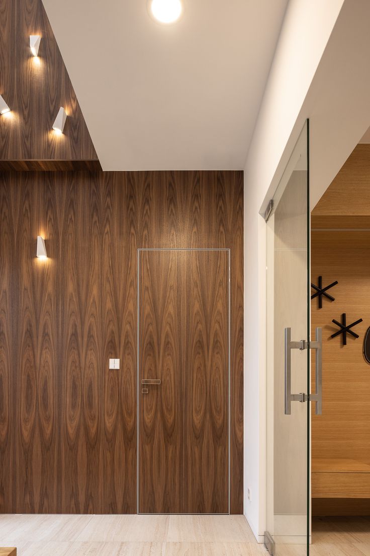 an empty room with wood paneling and lights on the wall, along with a glass door