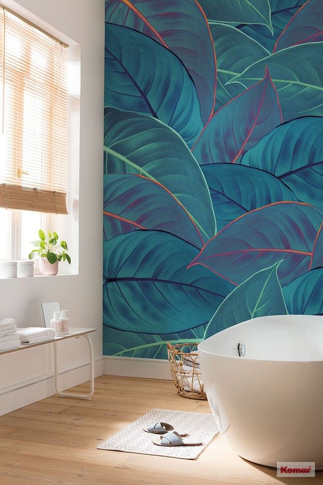 a bath tub sitting next to a wall covered in green leafy art on it's side