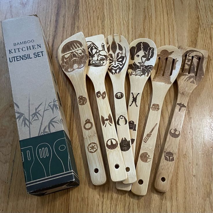 five wooden spoons with designs on them sitting next to a package of kitchen utensils