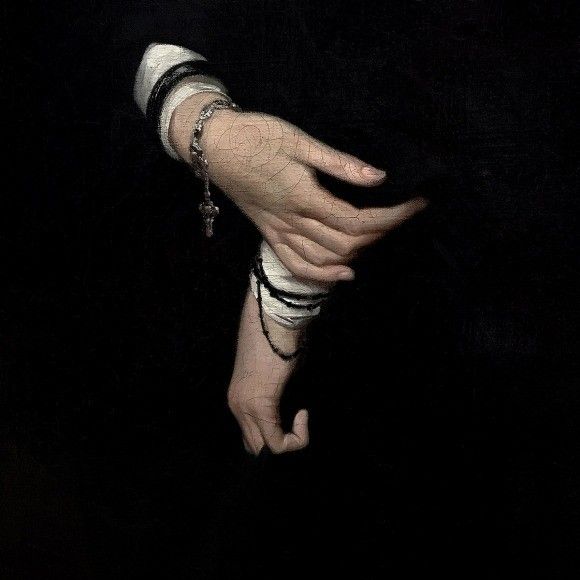 a woman's hand with bracelets and rings on her wrist in the dark