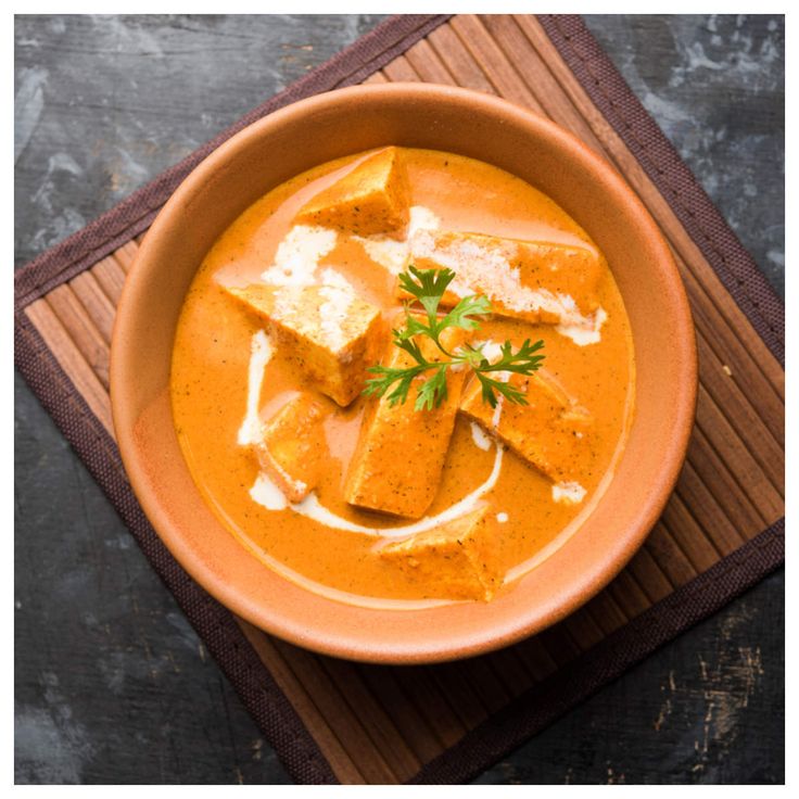 a bowl of soup with croutons and cheese in it on a wooden mat