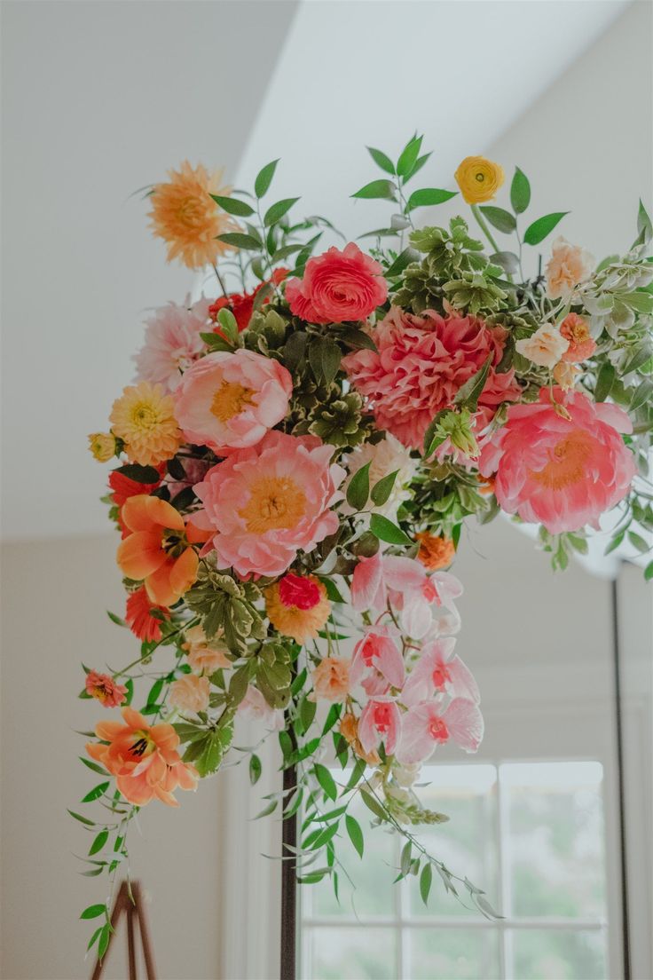 an arrangement of flowers is hanging from the ceiling