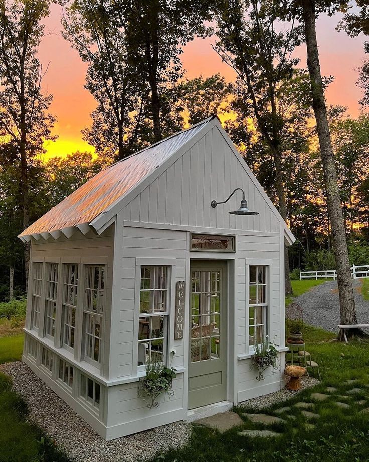 a small white building with windows and a door on the outside, surrounded by trees