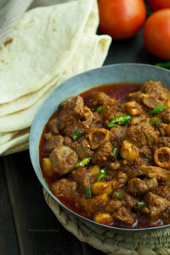 a close up of a bowl of food on a table with tomatoes and pita bread