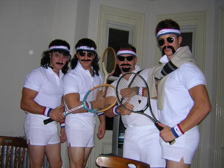 four people dressed in white holding tennis racquets and posing for the camera