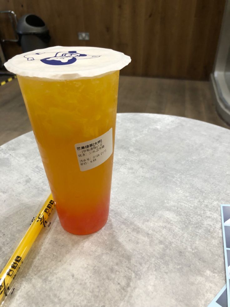 a plastic cup sitting on top of a table next to a yellow marker and pen