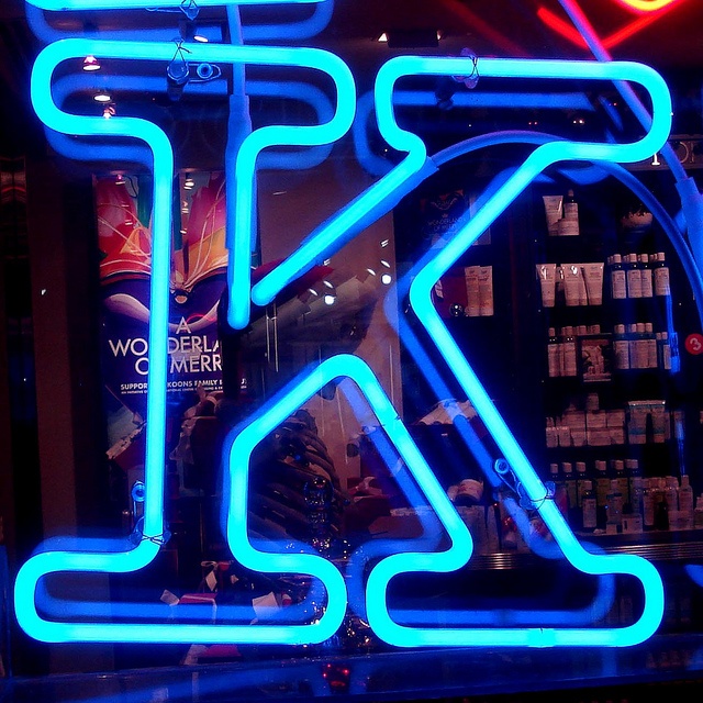 a neon sign in front of a store window with the letter k on it's side