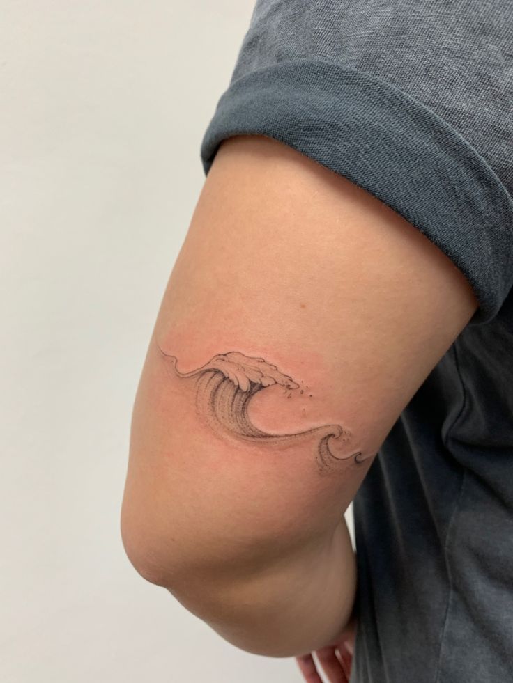 a woman's arm with a tattoo on it that is shaped like a wave