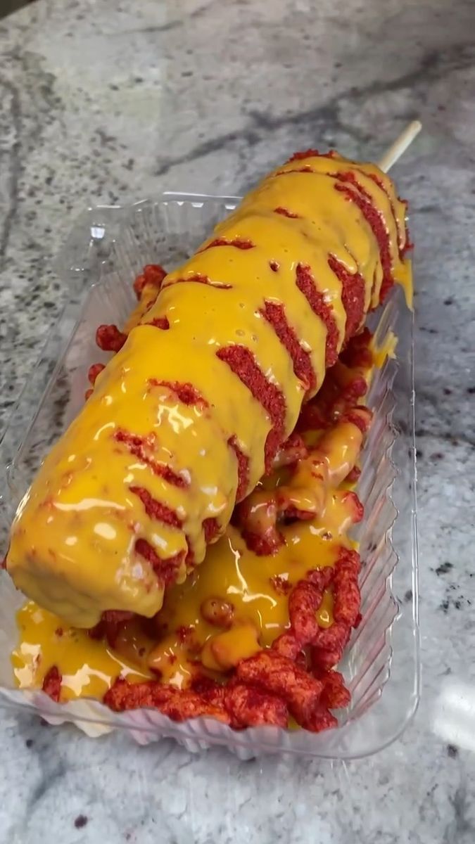 a hot dog covered in cheese and ketchup on a stick