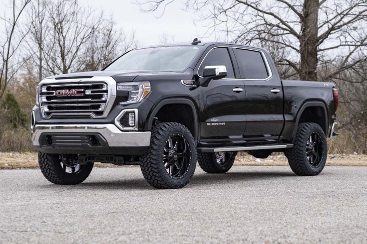 a black truck is parked on the side of the road in front of some trees