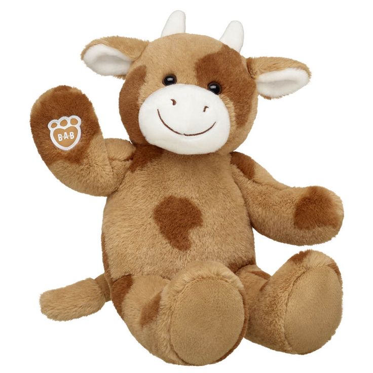 a brown and white cow stuffed animal sitting on top of a white surface with its arms in the air