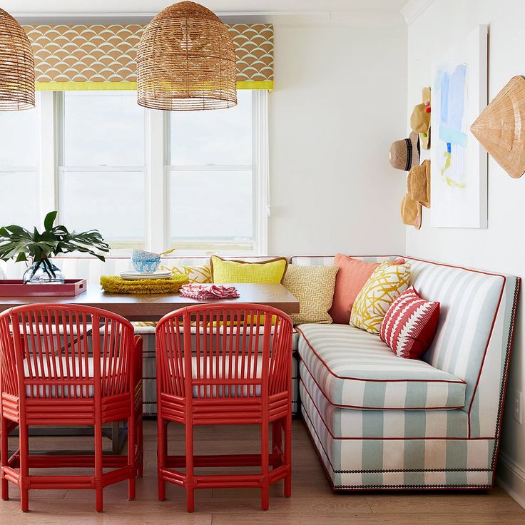 a living room with red chairs and a plaid couch in front of a table that has yellow pillows on it