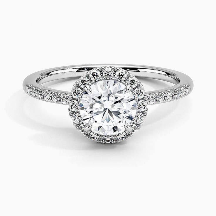 a white gold engagement ring with an oval halo setting and pave set diamonds on the band