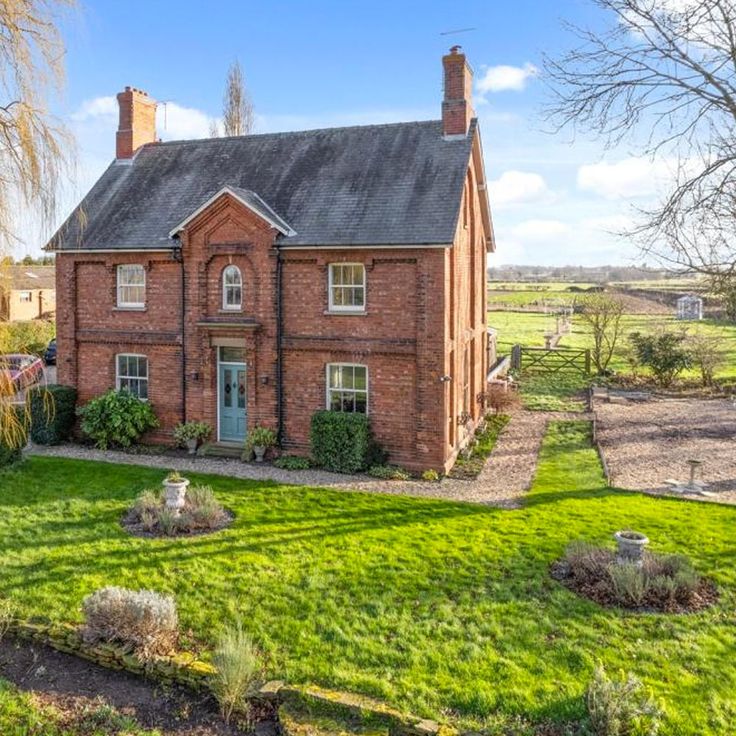 an old brick house with green grass in the front yard