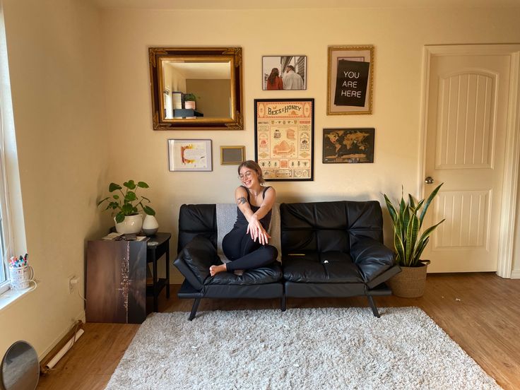 a woman sitting on top of a black couch in a living room