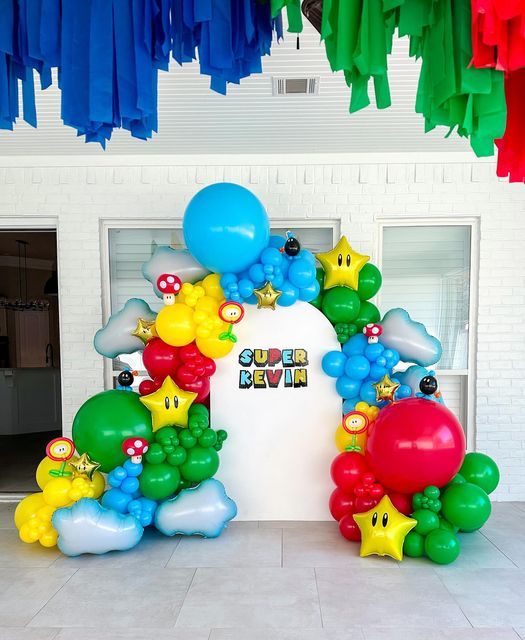 balloons and streamers decorate the entrance to a room with white brick walls, flooring and windows