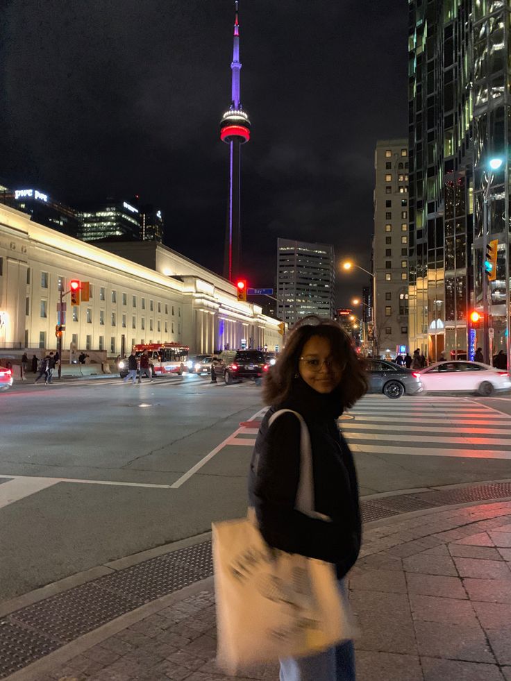 a woman standing in the middle of a street at night