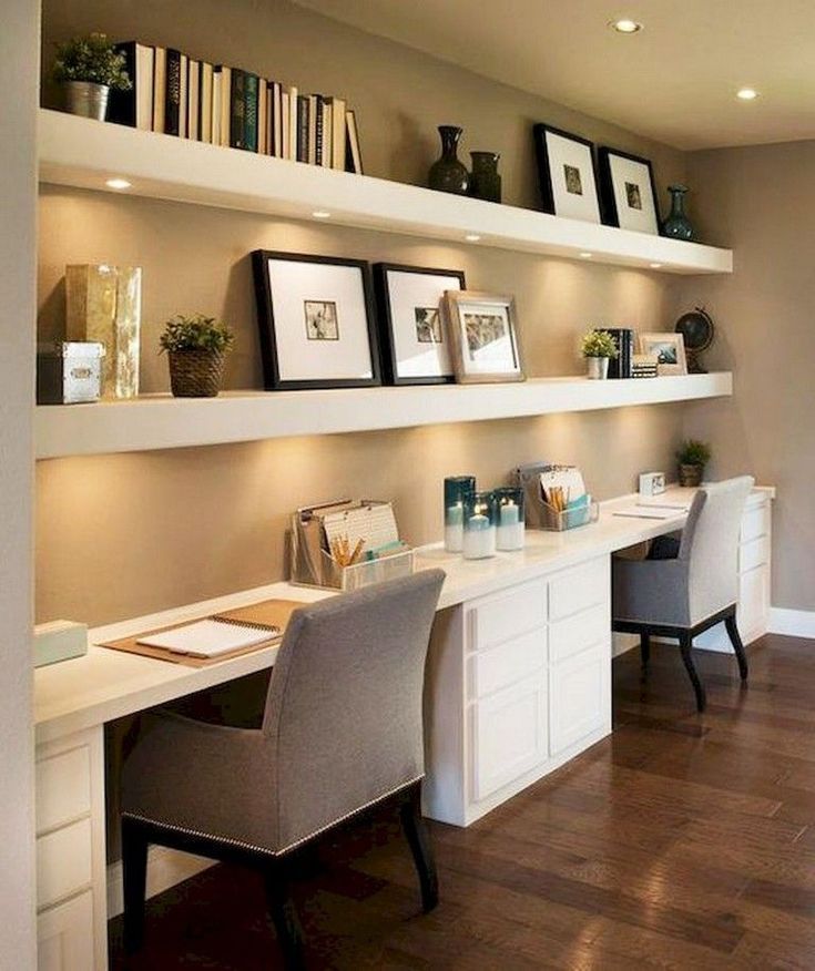 a home office with two desks and some bookshelves on the wall above them