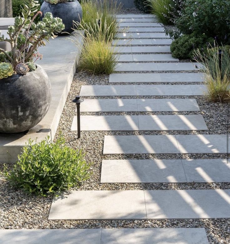 an outdoor garden with stone steps and plants in the center, surrounded by graveled walkways