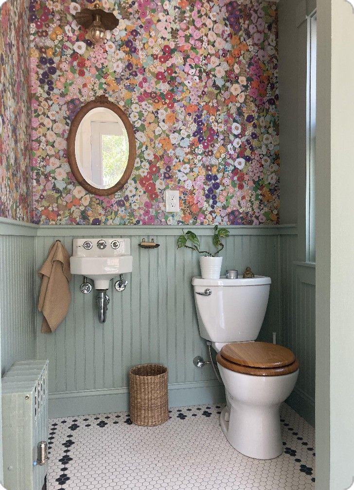 a toilet and sink in a small room with floral wallpaper on the walls behind it