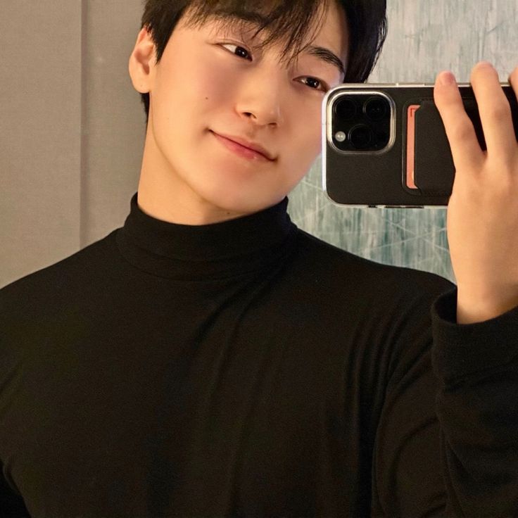 a young man taking a selfie with his cell phone in front of the camera