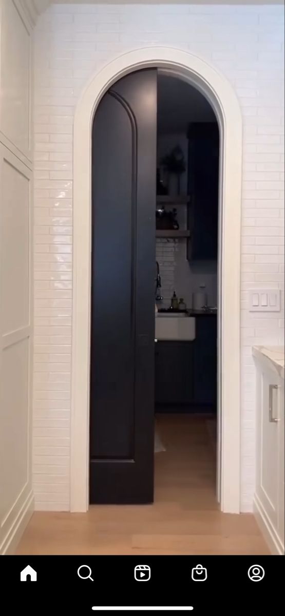 an open door leading into a kitchen with white walls and wood flooring on the side