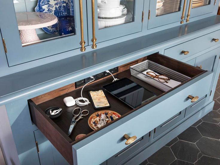 an open drawer in a blue kitchen with plates and utensils