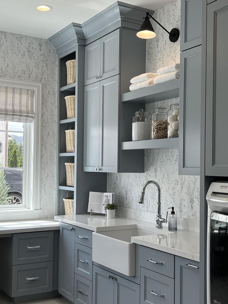 a kitchen with gray cabinets and white counter tops, along with a sink in the center