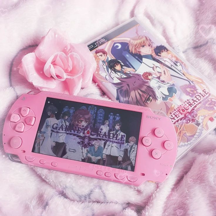 a pink nintendo wii game system sitting on top of a bed next to a flower