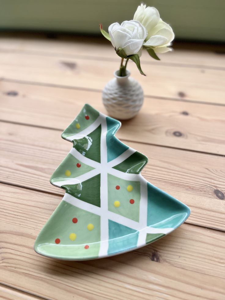 a small ceramic christmas tree sitting next to a vase with a white flower in it