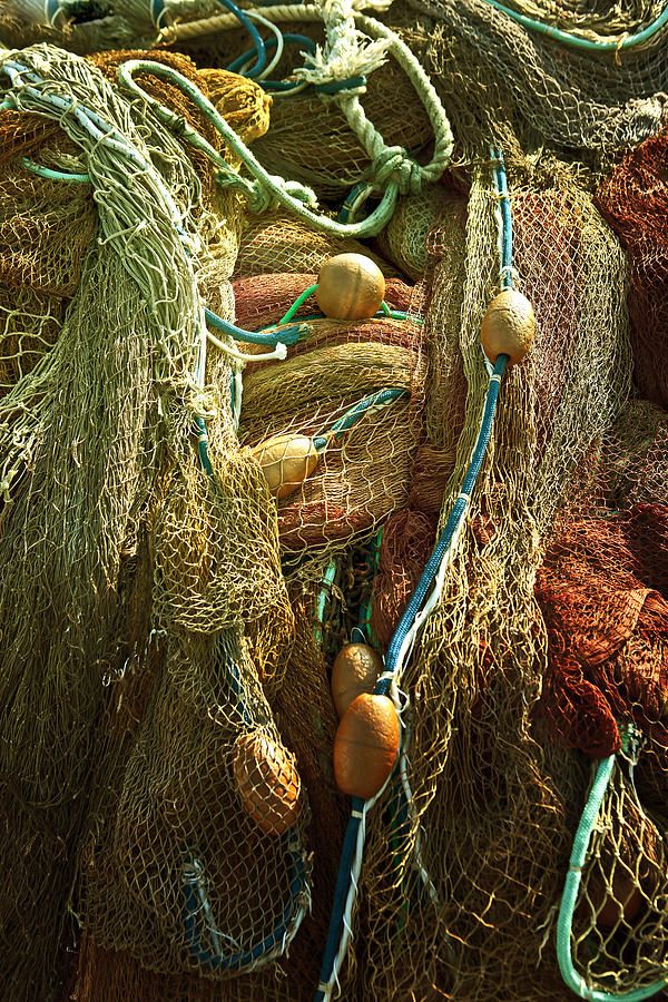 many fishing nets are stacked together on the ground with ropes and buoys attached to them