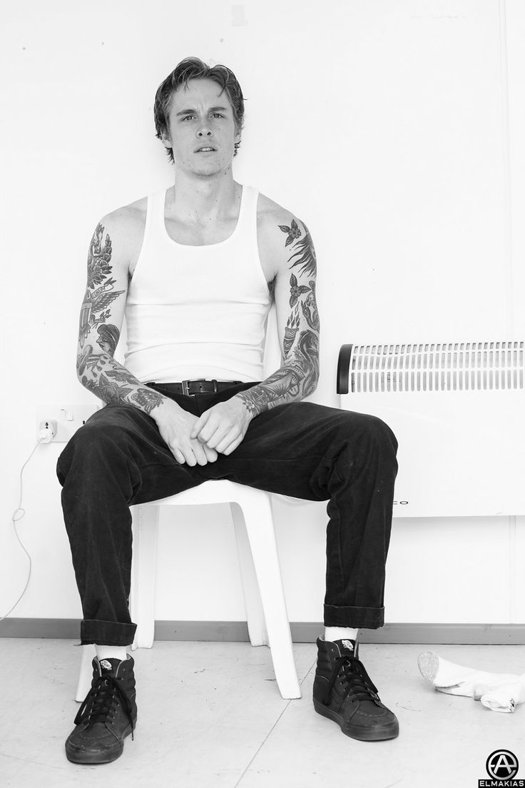 a man with tattoos sitting on a bench