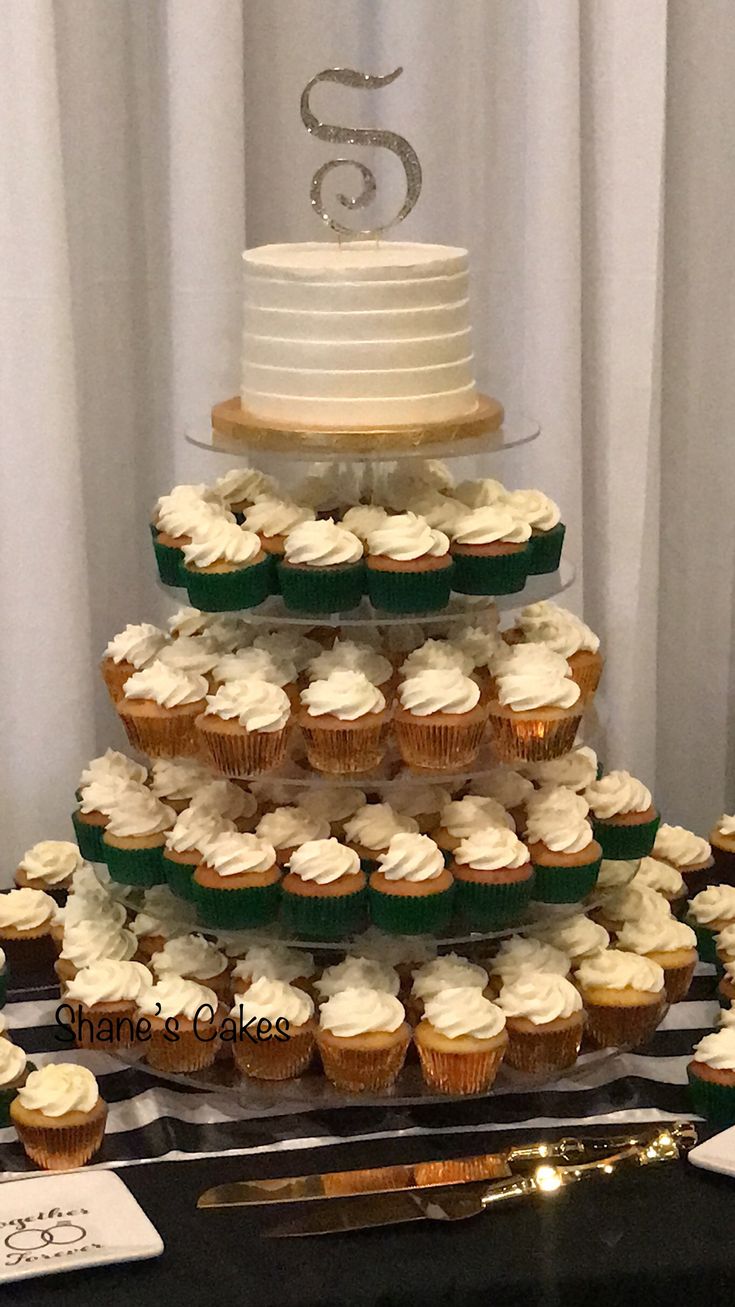 a wedding cake and cupcakes on a table