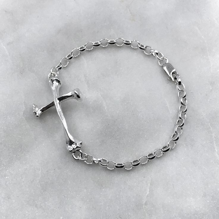 "The perfect accessory for a macabre sense of style. Solid sterling silver bone cross on a solid sterling silver chain bracelet.  Solid sterling silver bone cross on a solid sterling silver chain bracelet. Bone cross measures 4cm in length. Available in 7\" or 8\" bracelet lengths. The bracelet can be fastened to any link in the chain. 925 Sterling Silver. Each piece is handmade to order in the Jewel Thief Brighton atelier." Nickel Free Silver Cross Bracelets, Nickel Free Sterling Silver Cross Bracelets, Nickel-free Silver Cross Bracelets, Silver Cross Bracelet, Spiritual Style, Silver Nickel-free Cross Bracelet, Spiritual Silver Cross Bracelet, Sterling Silver Cross Rosary Bracelet, Sterling Silver Spiritual Rosary Bracelet With Cross, Spiritual Sterling Silver Cross Rosary Bracelet