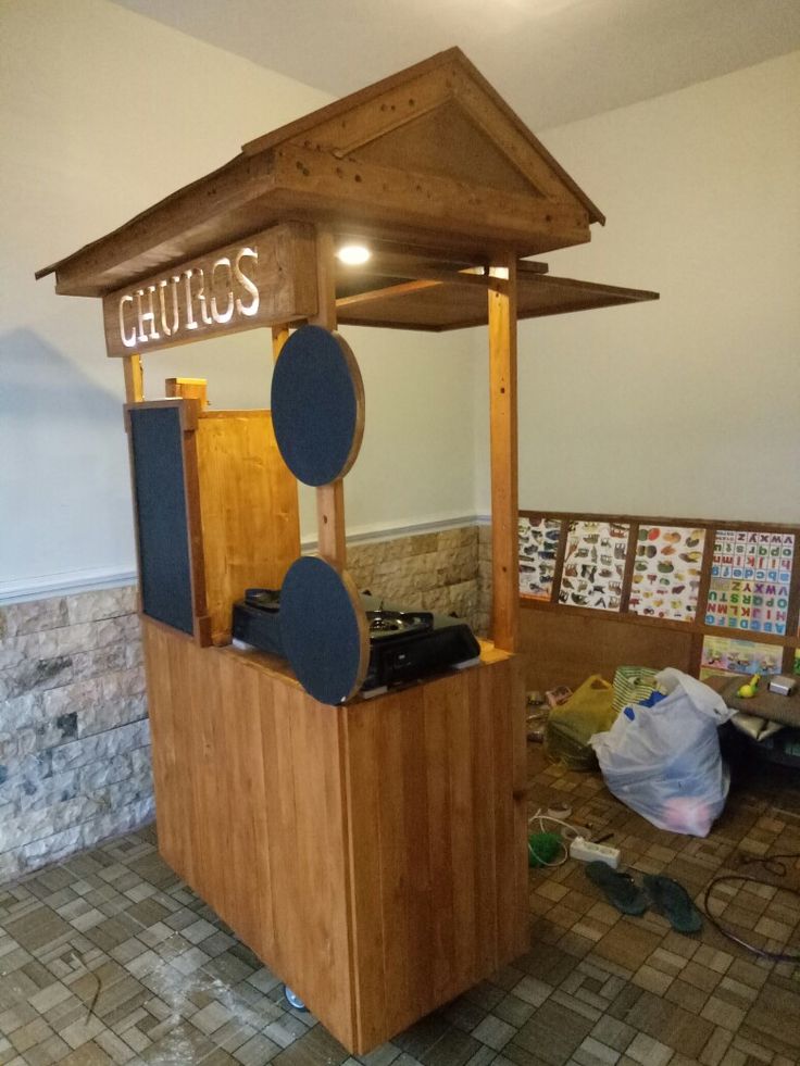 a small wooden kiosk with speakers on the front and back sides in an empty room