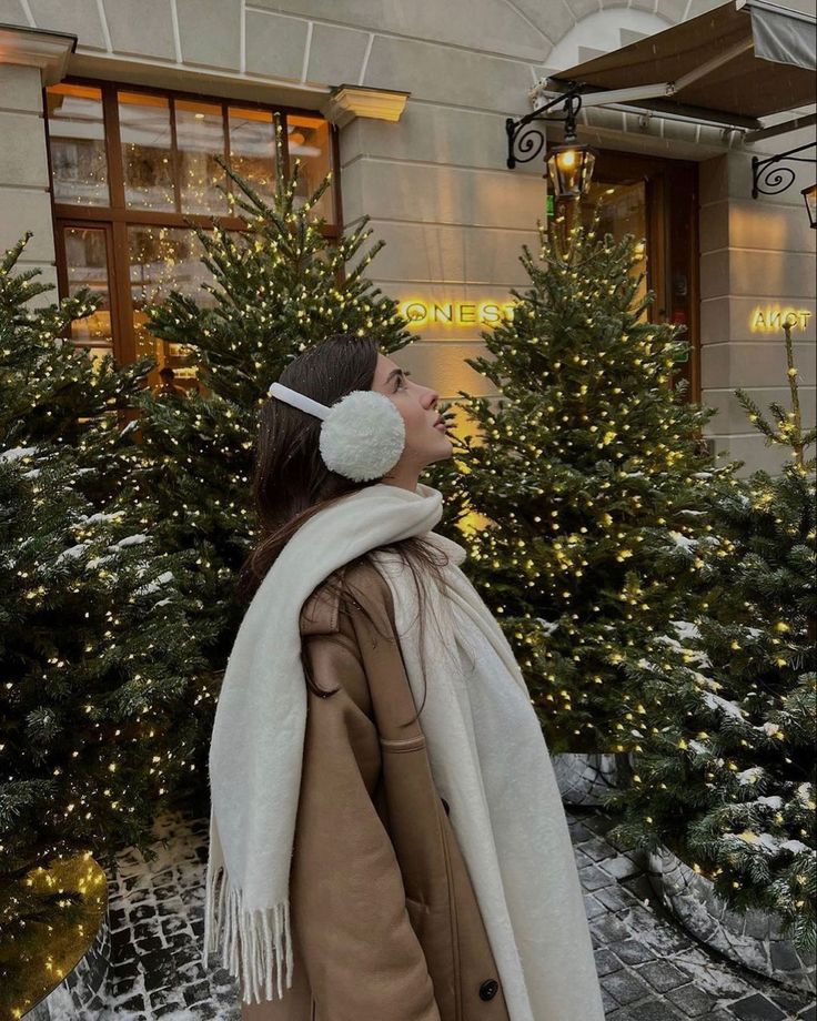 a woman standing in front of christmas trees