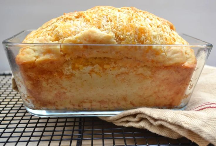 a loaf of bread sitting in a glass dish on top of a wire cooling rack