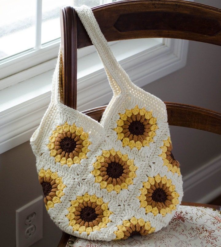 a crocheted sunflower purse sitting on top of a chair next to a window