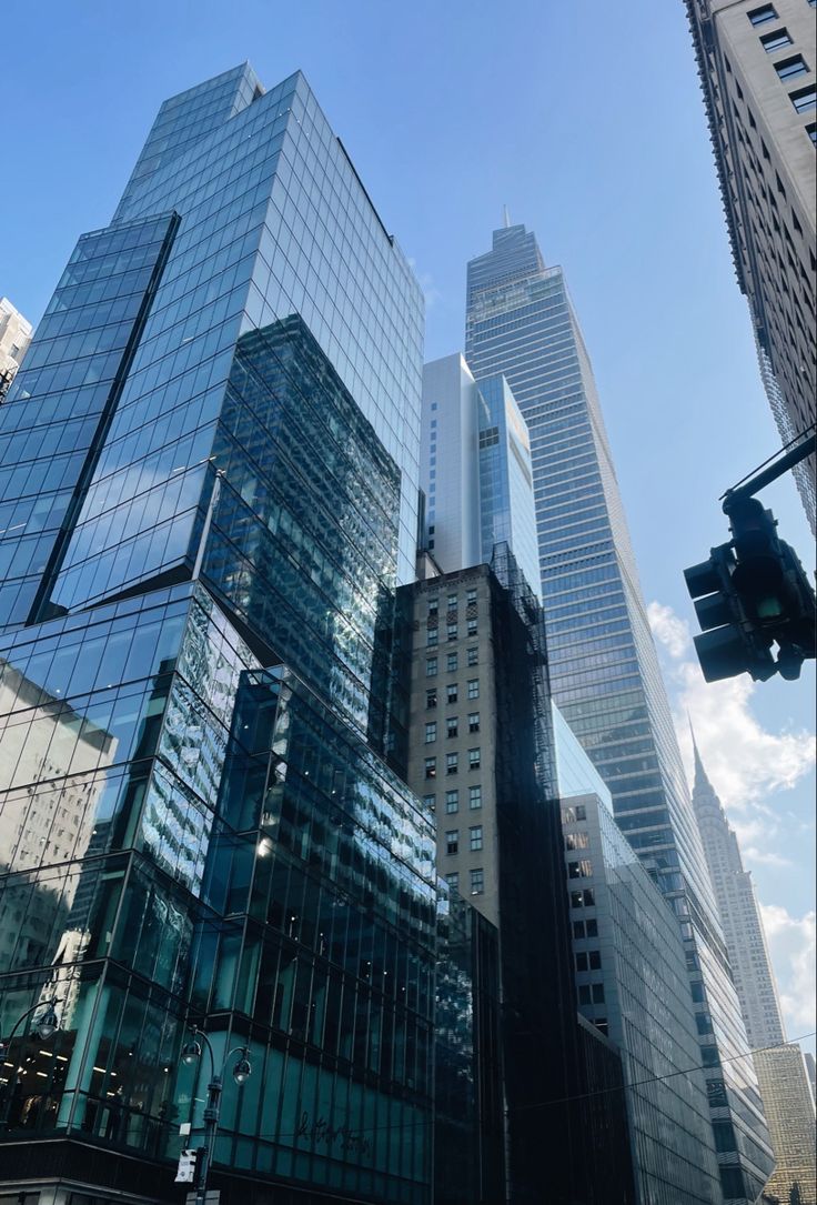 the skyscrapers are all glassy and very high in the city, with traffic lights on each side