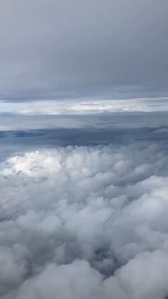 the view from an airplane looking down on some clouds and mountains in the distance,