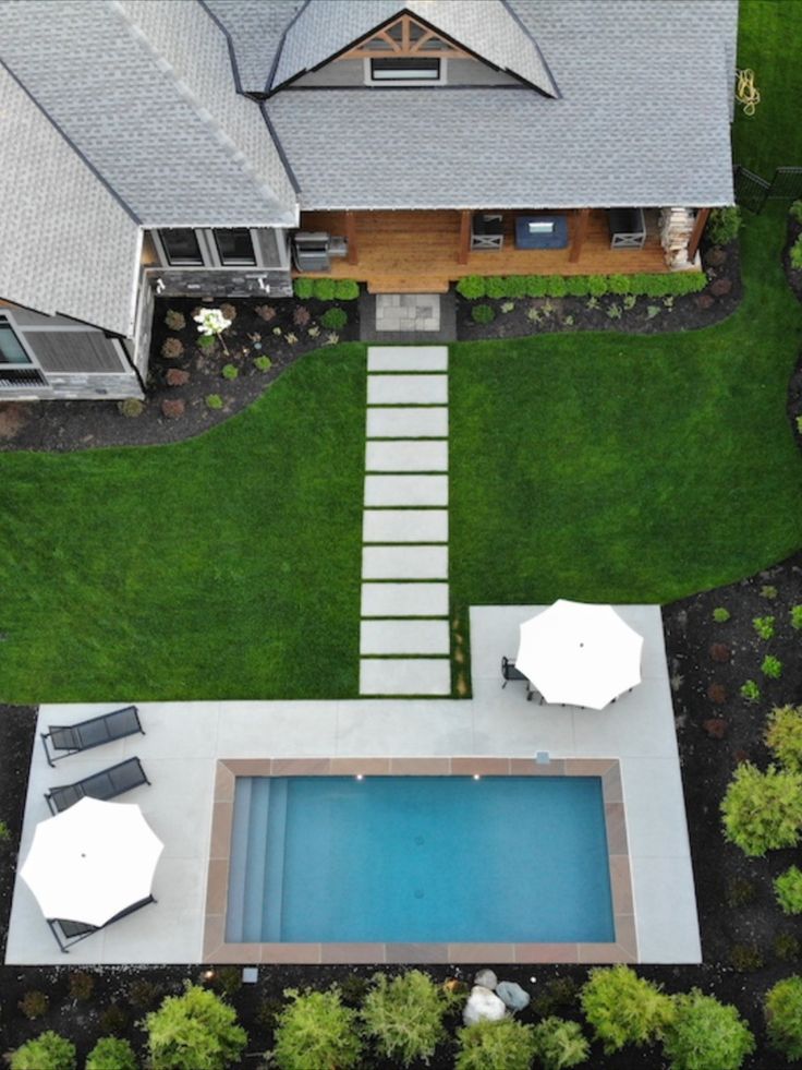 an aerial view of a house with a pool in the yard and some lawn chairs