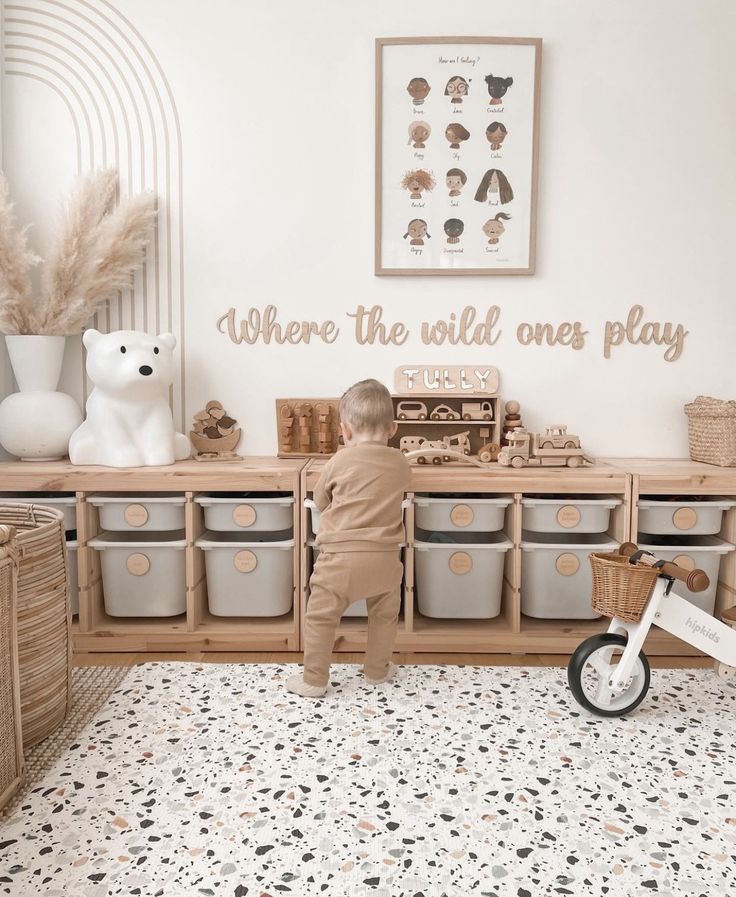 a little boy sitting on top of a wooden shelf next to toy bins and baskets