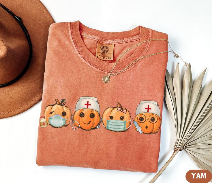 Pumpkin Nurse Halloween Comfort Colors Shirt, Vintage Theme Spooky Season RN TShirt, Boo Boo Crew Shirts, Halloween Nursing, Hospital Party T-Shirt, Spooky Fall Nurse T Shirt, Nurse Gifts Halloween Tees ✧ WHY  YOU'LL  LOVE IT ✧  ⋒ Comfort Colors® tees are garment-dyed shirts that are timeless classics and will never pile.  ⋒ Trendy retro vintage look and gorgeous colors.  ⋒ Amazingly soft and comfy. Perfect with any shorts, skirts, jeans, leggings, or nothing but undies around the house. ⋒ Created with quality in mind, it's made from 100% ring-spun cotton. ⋒ Will last for years with its double-needle stitched neckline, sleeves, and bottom-hems. ⋒ Garment is made with the most expensive dyeing process, reducing shrinking up to 99%. ⋒Comfort Colors®, through Gildan's Community Investment Pro Orange Crew Neck Top With Character Print, Cute Orange Tops With Cartoon Print, Fun Orange Long Sleeve T-shirt, Funny Orange Tops For Fall, Funny Orange Top For Fall, Orange Tops With Character Print For Fall, Cute Orange Crew Neck Top, Fall Orange Tops With Character Print, Orange Character Print Tops For Fall