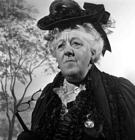 an old woman wearing a black hat and dress with feathers on it's head