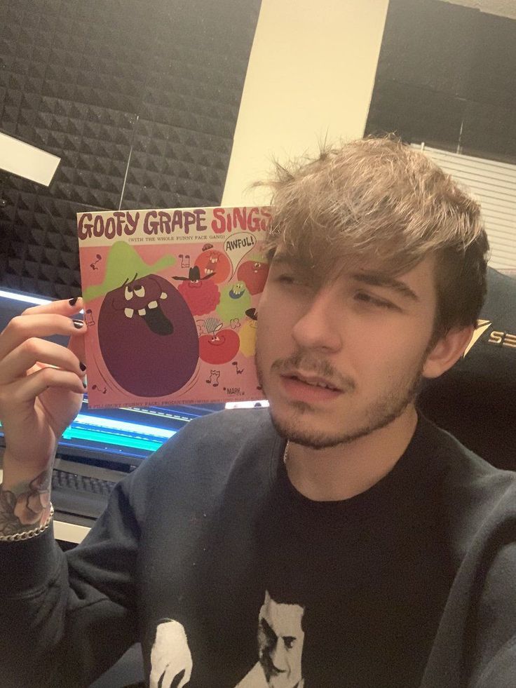 a young man holding up a book in front of his face and looking at the camera